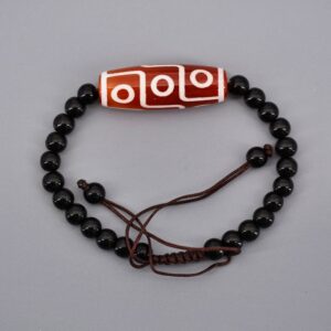 Adoptez le bracelet tibétain perle dzi de la Boutique Zen Himalayan-eshop. Un bijou unique combinant agate rouge à 9 yeux et perles d'onyx noir, symbole de richesse et de santé. Plongez dans l'art sacré du bouddhisme avec ce bracelet réglable et artisanal. Commandez le vôtre dès aujourd'hui !